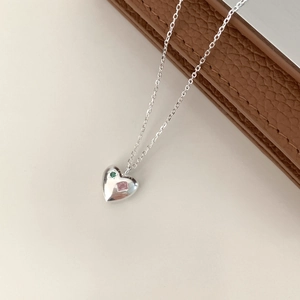 Detail view of heart-shaped silver necklace featuring pink and green gemstone accents