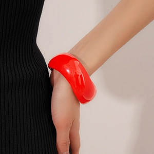 Detailed shot of a wide red resin bangle featuring an irregular wavy design on a model