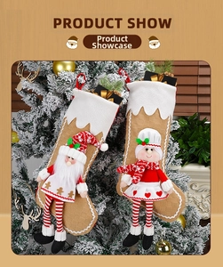 Close-up of hanging Christmas stockings with Santa and doll figures on snowy pine tree