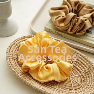 Detail of satin fabric hair scrunchies in gold and bronze on a woven tray setting