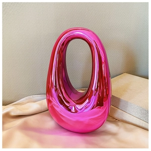 Macro detail of oval cutout handbag in metallic rose red on beige silk fabric