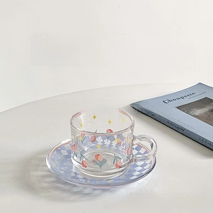 Detail of tulip checkerboard glass cup and saucer set on minimalist white surface