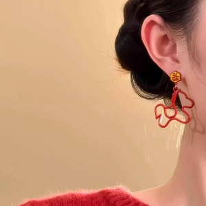 Red dog dangle earrings with gold Fu character studs shown on a model's ear