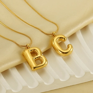 Detailed view of bubble initial B and C gold pendants on sleek snake chains for women