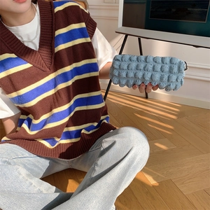 Close-up of light blue bubble textured pouch held in hand against wooden floor