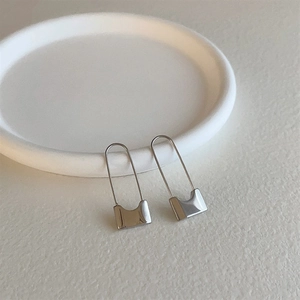 Minimalist silver geometric safety pin earrings for women on a white stone tray