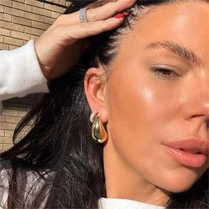 Polished gold water drop hollow earrings for women shown on a model in natural light