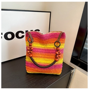 Close-up of rainbow woven straw bucket bag with gradient stripes and wooden bead handle