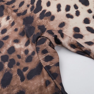 Macro shot of sharp leopard print details and stitching on polyester fabric jumpsuit