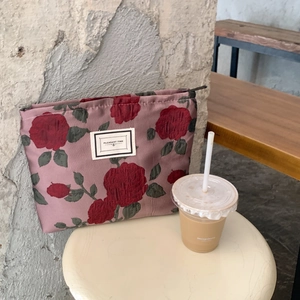 Detailed close-up of retro rose brocade makeup bag with PLEASANT TIME label