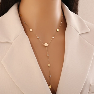 Detail view of gold Y-shaped necklace with round discs and zircon stones on a model