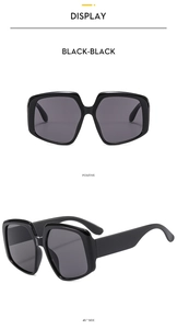 Detail view of large irregular black frame sunglasses with dark grey lenses in 45-degree angle