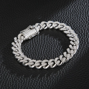 Silver Cuban link bracelet for men with clear stones on a black leather texture background