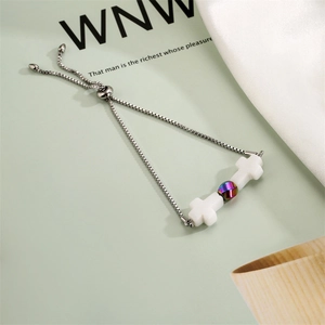 Detail of adjustable stainless steel bracelet featuring white crosses and rainbow bead