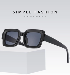 Detail of classic black square sunglasses on a geometric stand with matte finish texture