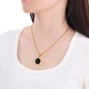 Detail of elegant gold necklace with black clover pendant on female neck