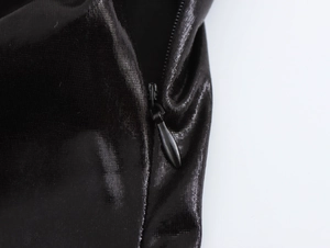 Detail view of a hidden zipper on a black sequin bodycon dress with glossy finish