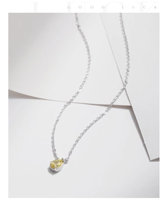 Macro shot of silver necklace with yellow pear-cut gemstone pendant on white background