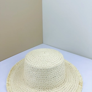 Detail of woven straw hat featuring frayed fringe edges and fine braided texture