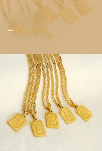 Detail of gold square letter pendants A to E on a twisted cable chain necklace