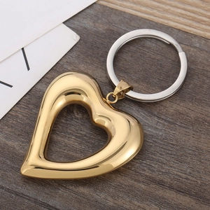 Gold heart-shaped hollow keychain pendant with polished finish on dark wood background