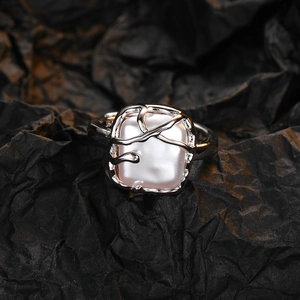 Anello ramo d'argento con perla bianca quadrata irregolare su sfondo nero materico
