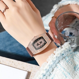 Detail of tonneau-shaped diamond-encrusted watch case with a brown silicone strap