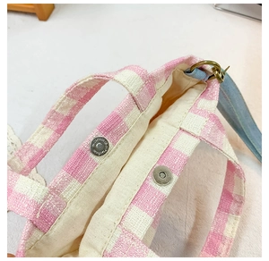 Detail of pink gingham canvas bag featuring internal magnetic clasp and white lining