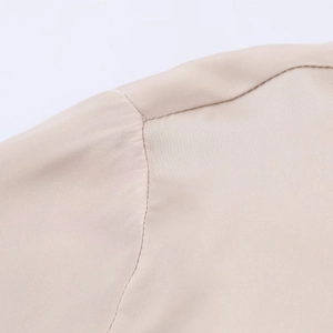 Close-up of shoulder seam detail on a beige satin blouse with smooth woven texture