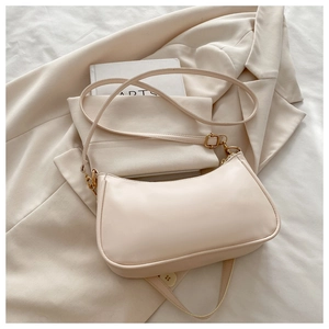 Detail of a creamy beige crescent underarm bag on a suit jacket for professional styling
