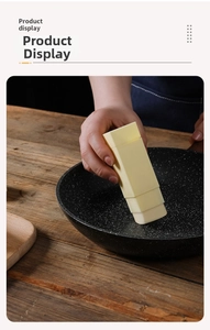 Close-up of handheld rotating butter spreader stick applying butter to a black skillet