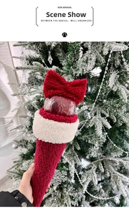 Close-up of lamb wool Christmas apple gift bag with red bow on snowy tree background
