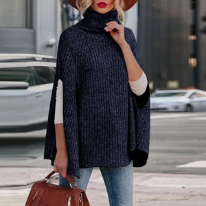 Dettaglio del maglione a mantella in maglia blu scuro con collo alto e vestibilità ampia