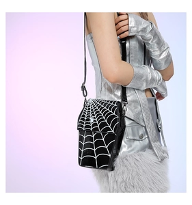 Detail of black glossy PU crossbody bag featuring white spider web print and thin strap