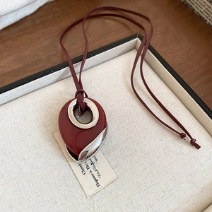 Detail of burgundy teardrop pendant with silver trim on brown leather cord