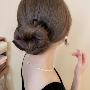 Détail d'un pic à cheveux noir ondulé fixant un chignon bas élégant sur une femme
