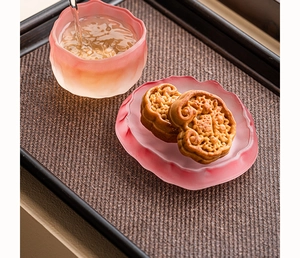 Close-up of pink frosted lotus-shaped glass tea cup and saucer during tea pouring