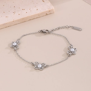 Detailed shot of silver butterfly bracelet with pearls on a textured stone display