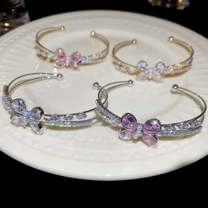 Detail of zircon butterfly open bracelets with pink crystals and pearls on a white plate