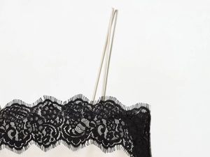 Détail du haut en satin ivoire avec bordure en dentelle noire et fines bretelles