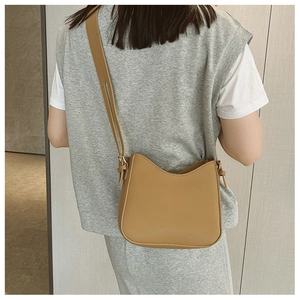 Sac bandoulière marron en cuir PU avec bord ondulé et boucle dorée sur modèle