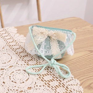 Detail of mint green straw cross-body bag with large cream lace bow and zipper closure