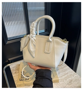 Detail of white lychee leather bucket bag with gold hardware and silk scarf handle