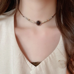 Close-up of ethnic style pendant necklace with stone, wood beads on beige top