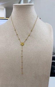 Detail of 18K gold Y-necklace featuring a clover pendant and beads on a mannequin