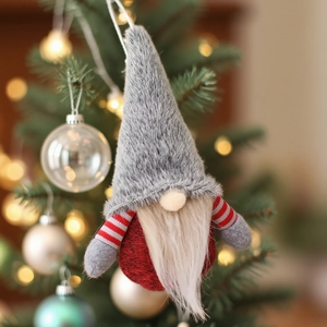 Handmade Christmas forest gnome ornament in dark grey and red hanging on a tree