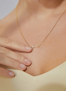 Macro shot of minimalist gold cross necklace with pavé cubic zirconia on model neck