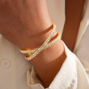 Detail of luxury gold crisscross bracelet with sparkling pavé crystals on a female wrist