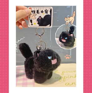 Close-up of black fluffy cat plush keychain with blue eyes and silver metal hardware