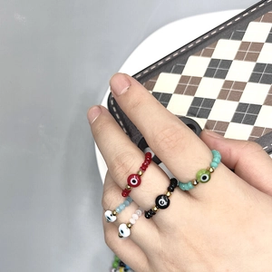 Elastic beaded evil eye rings in red, black, and green colors worn by model on grey background
